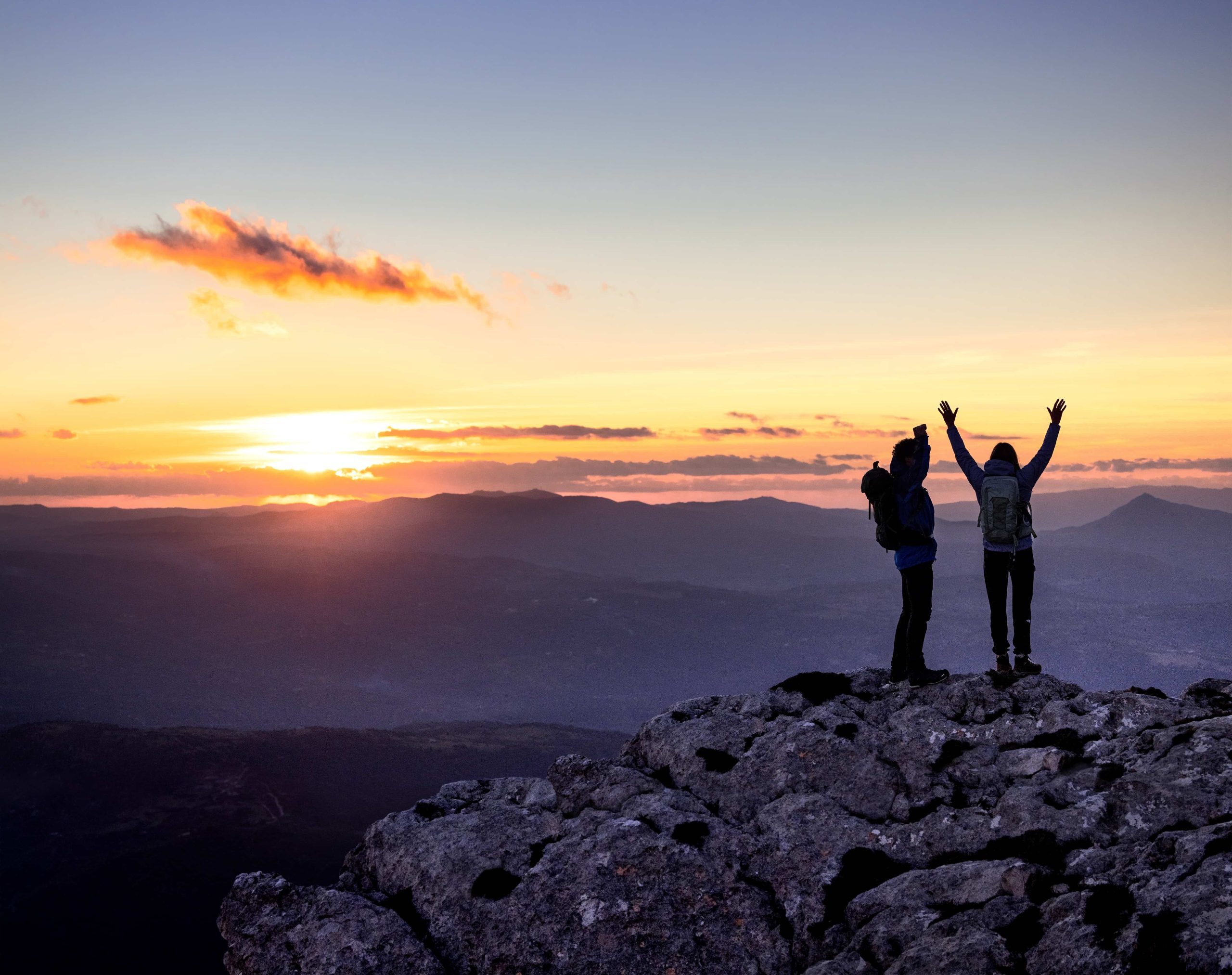 people on top of a mountain with their arms up