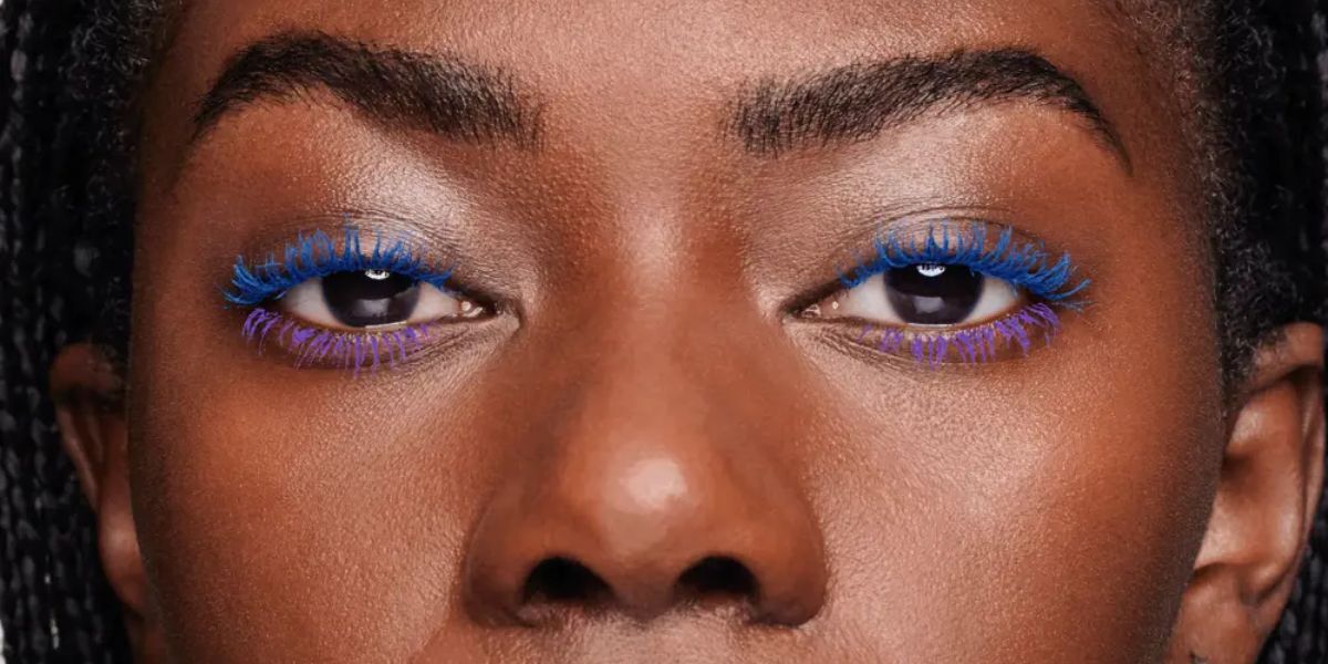 An Oriflame marketing image of a woman's eyes with blue and purple mascara.