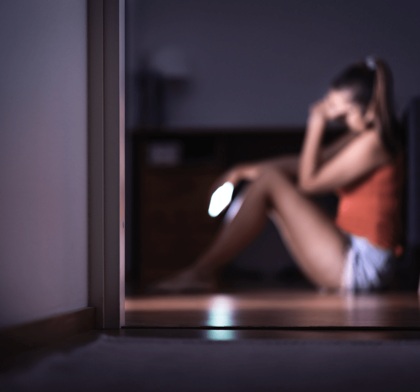 women sitting against wall with hand on head