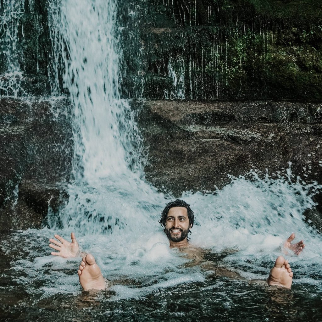 man lying down by waterfall