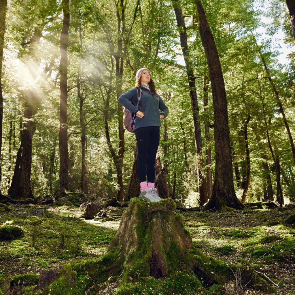 woman smiling standing on tree stump