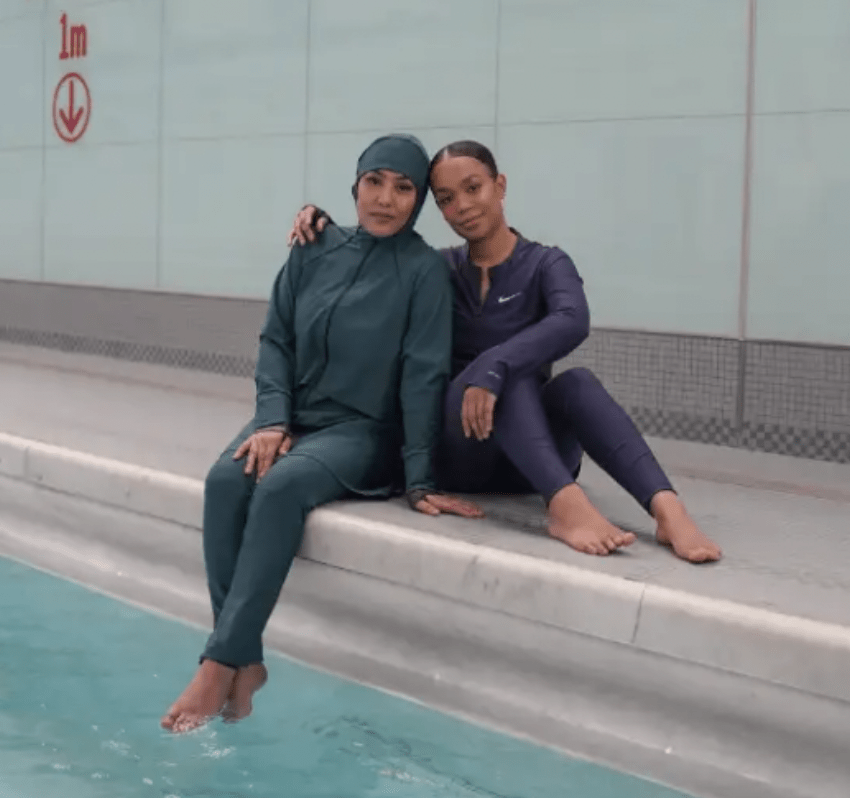 two women posing by swimming pool wearing nike swim swimwear