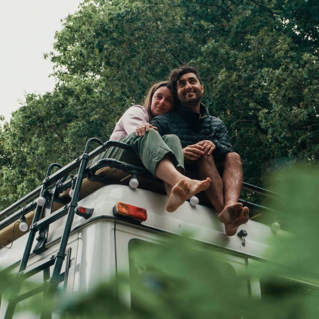 couple sitting on top of campervan