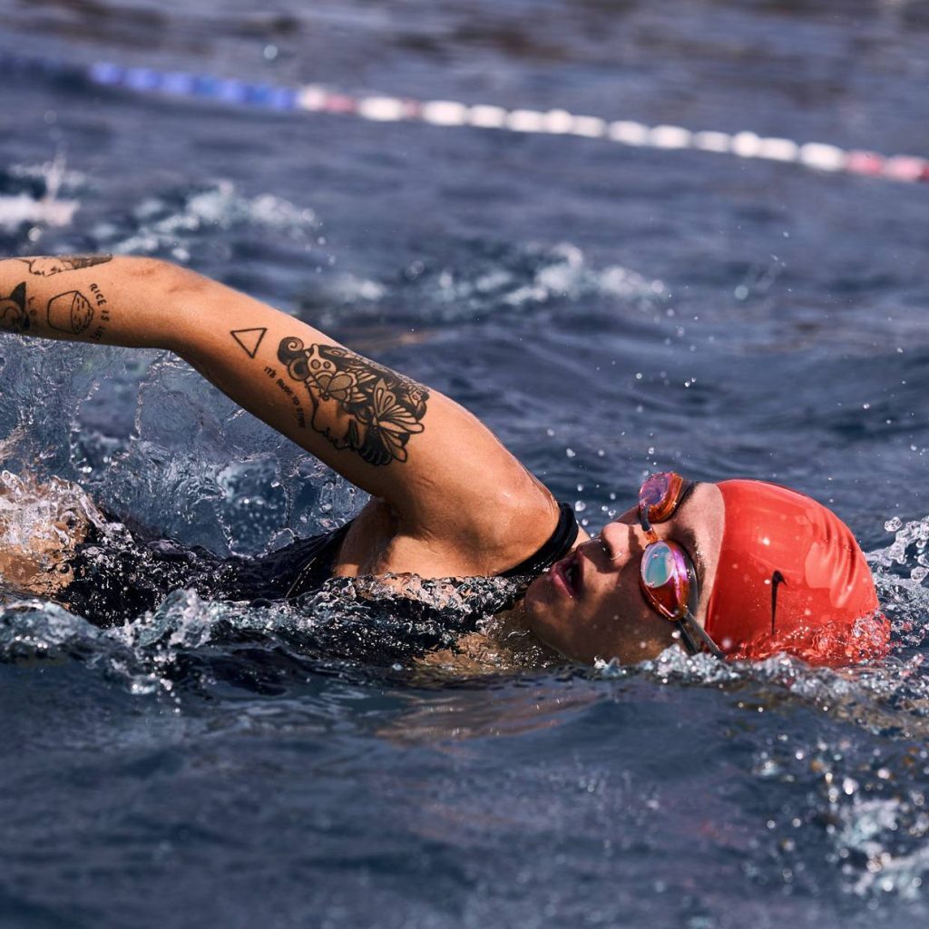 woman swimming wearing nike swim swimming cap