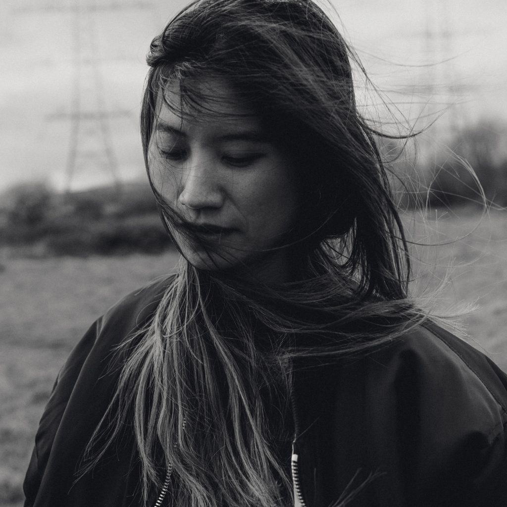 woman in field with wind brushing her hair across her face