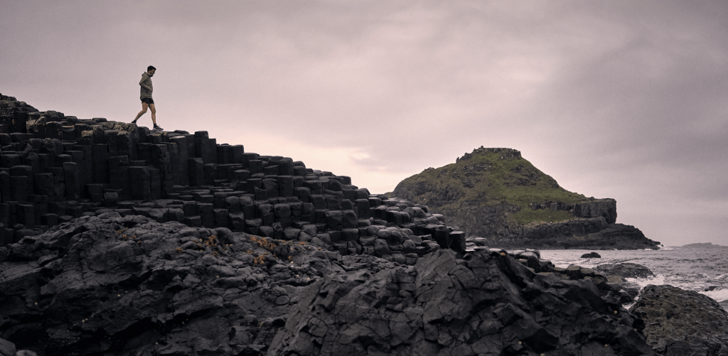 man walking on rocks by river in merrell trainers