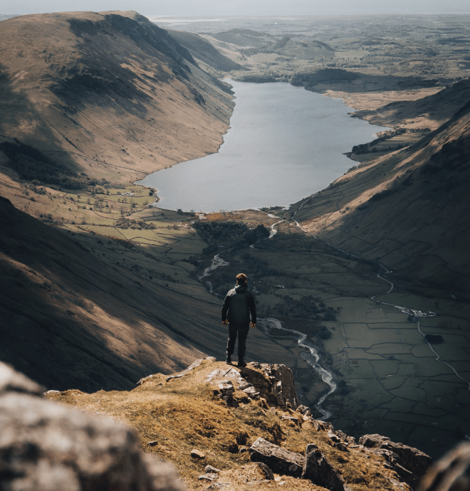 man hiking in countryside atop a hill