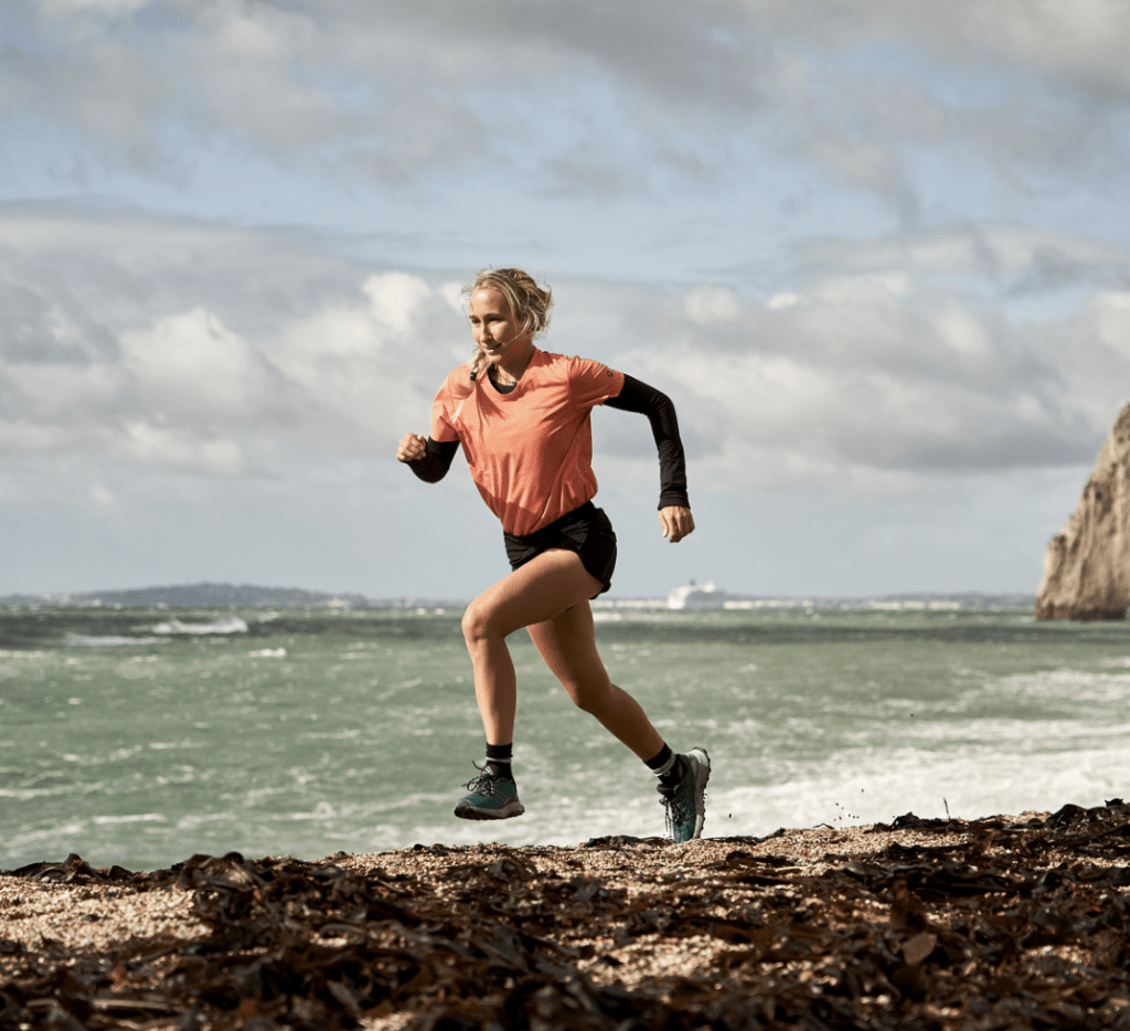 woman running in merrell trainers alongside beach