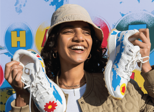 woman holding two merrell know your code trainers