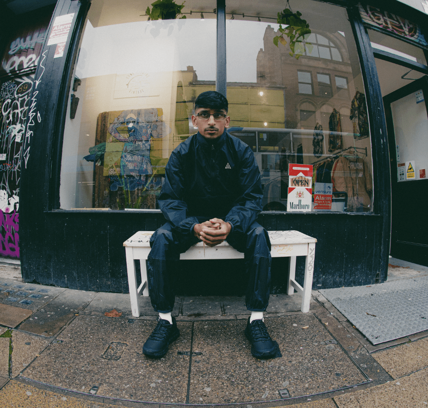 man sitting down on wooden bench wearing merrell trainers