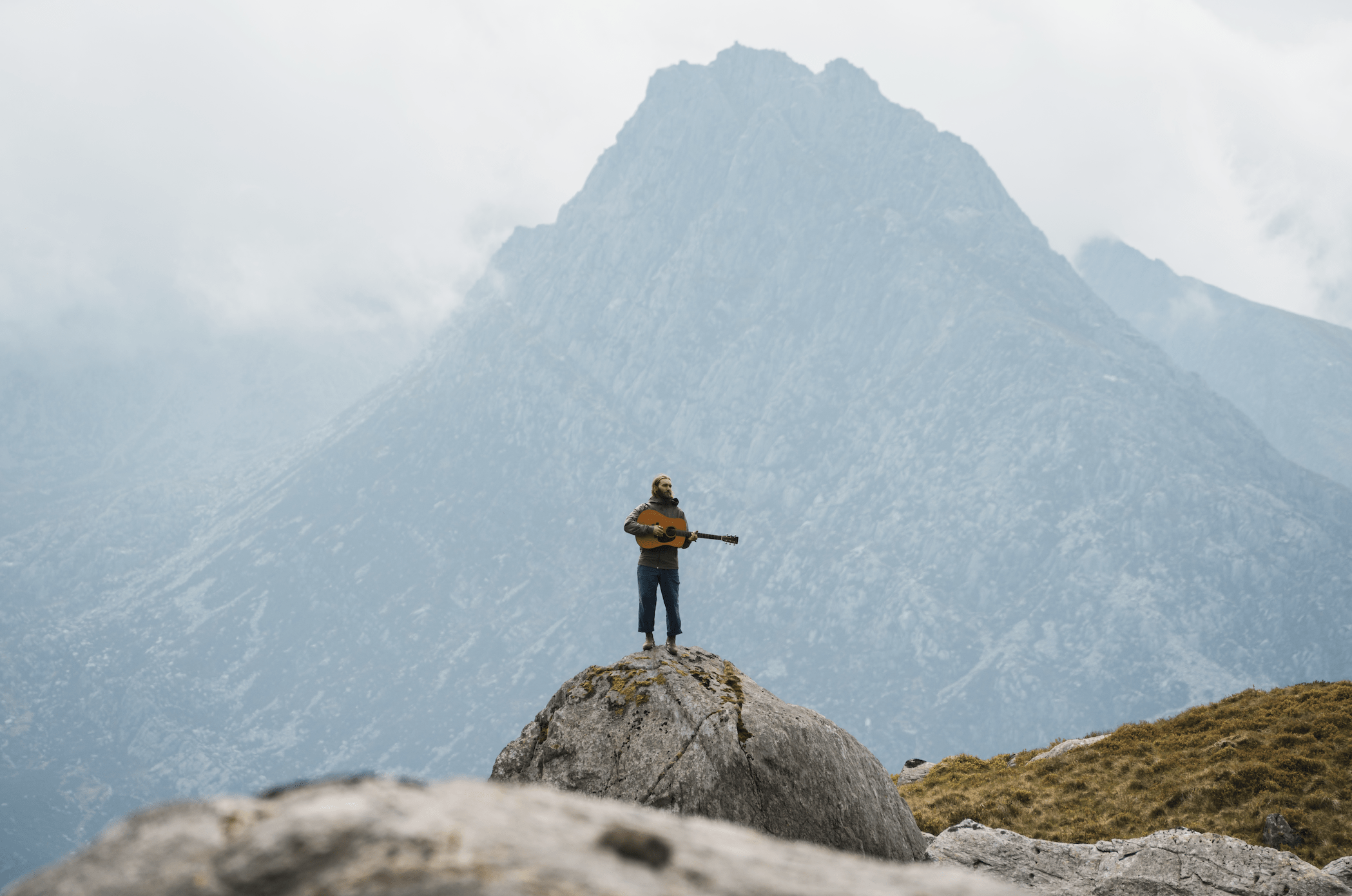 Man playing guitar with mountain in the background