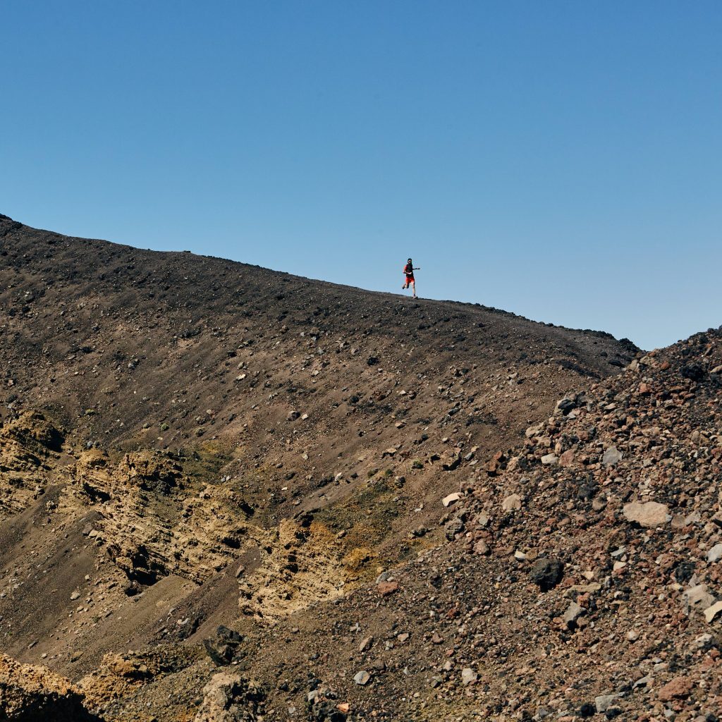 man running along hill in merrell trainers