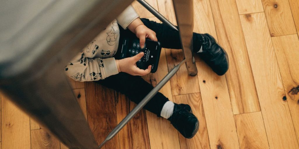 child on phone sitting on floor