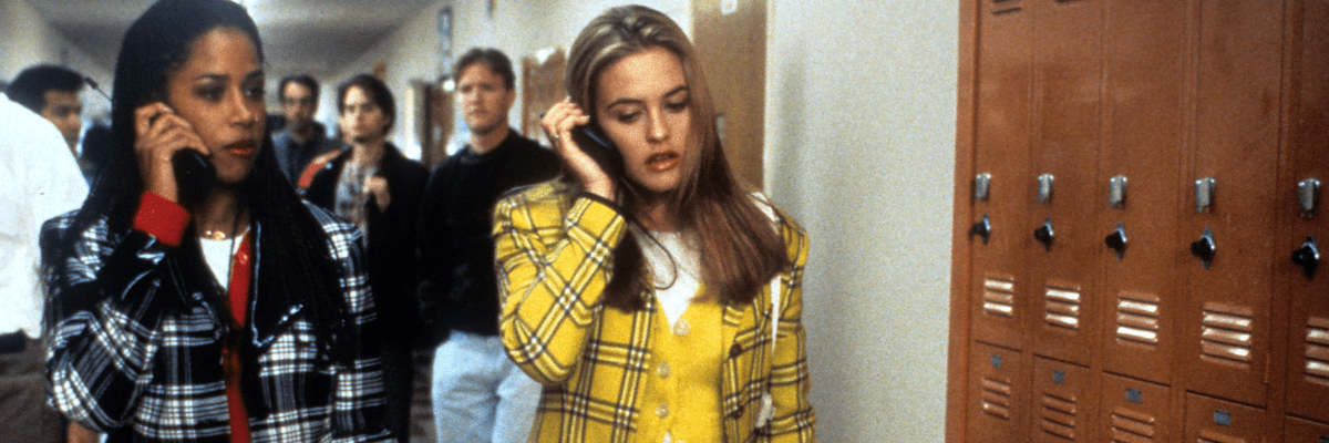 girls on phones walking through school corridor in plaid outfits in film called clueless