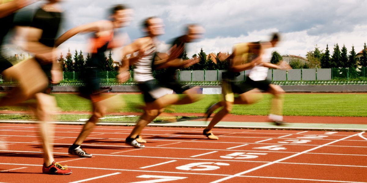 A blurred image of people running on athletics track.