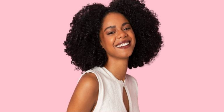 bellissima image of woman with curly hair smiling in white top
