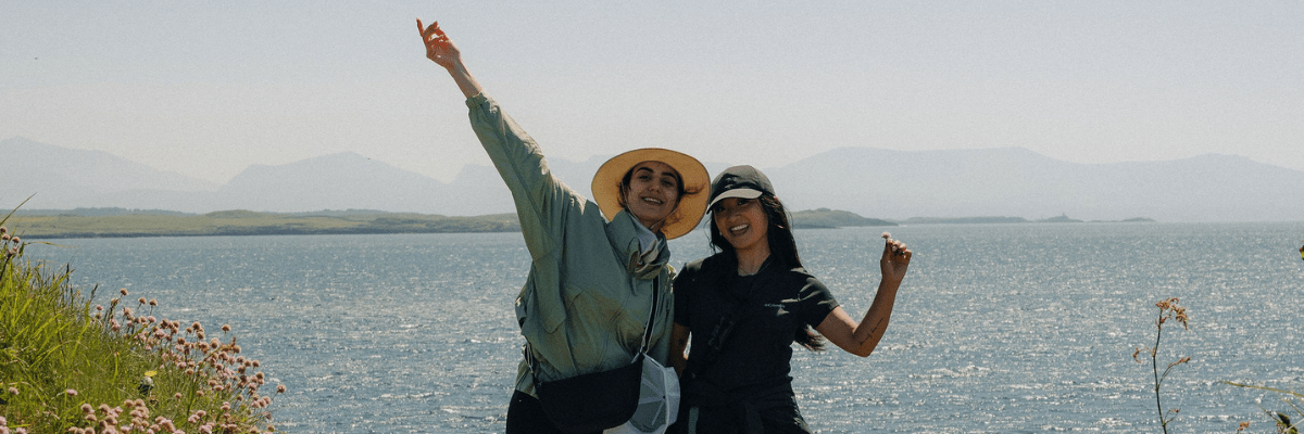 Two woman pose together smiling with their hands in the air at Columbia's HikeFest 2025 with Brandnation