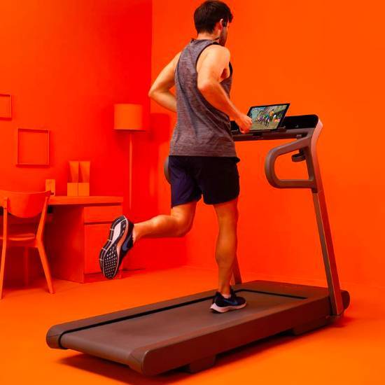 man running on running machine with zwift interface