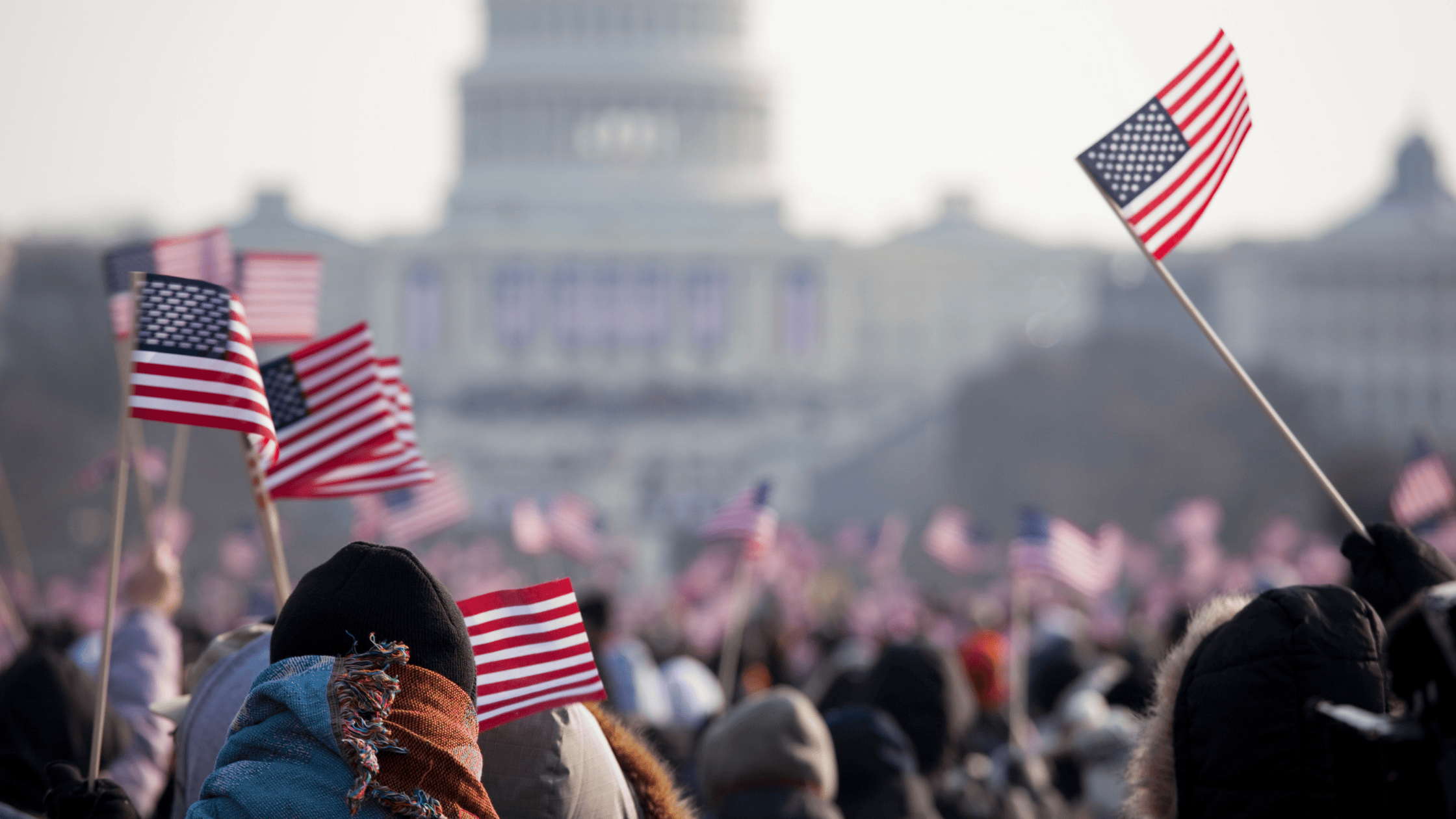 American flags waving in a crowd with a view of a building